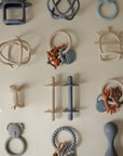 A grid of twelve mushie Teething Rings in various shapes and muted colors.