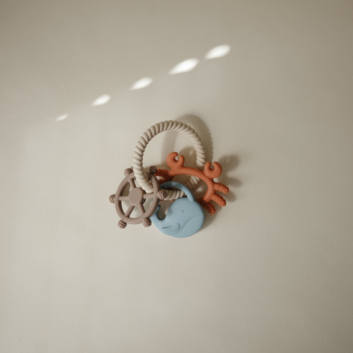 Mushie Teething Ring set featuring a whale, a crab, and a ship’s wheel.