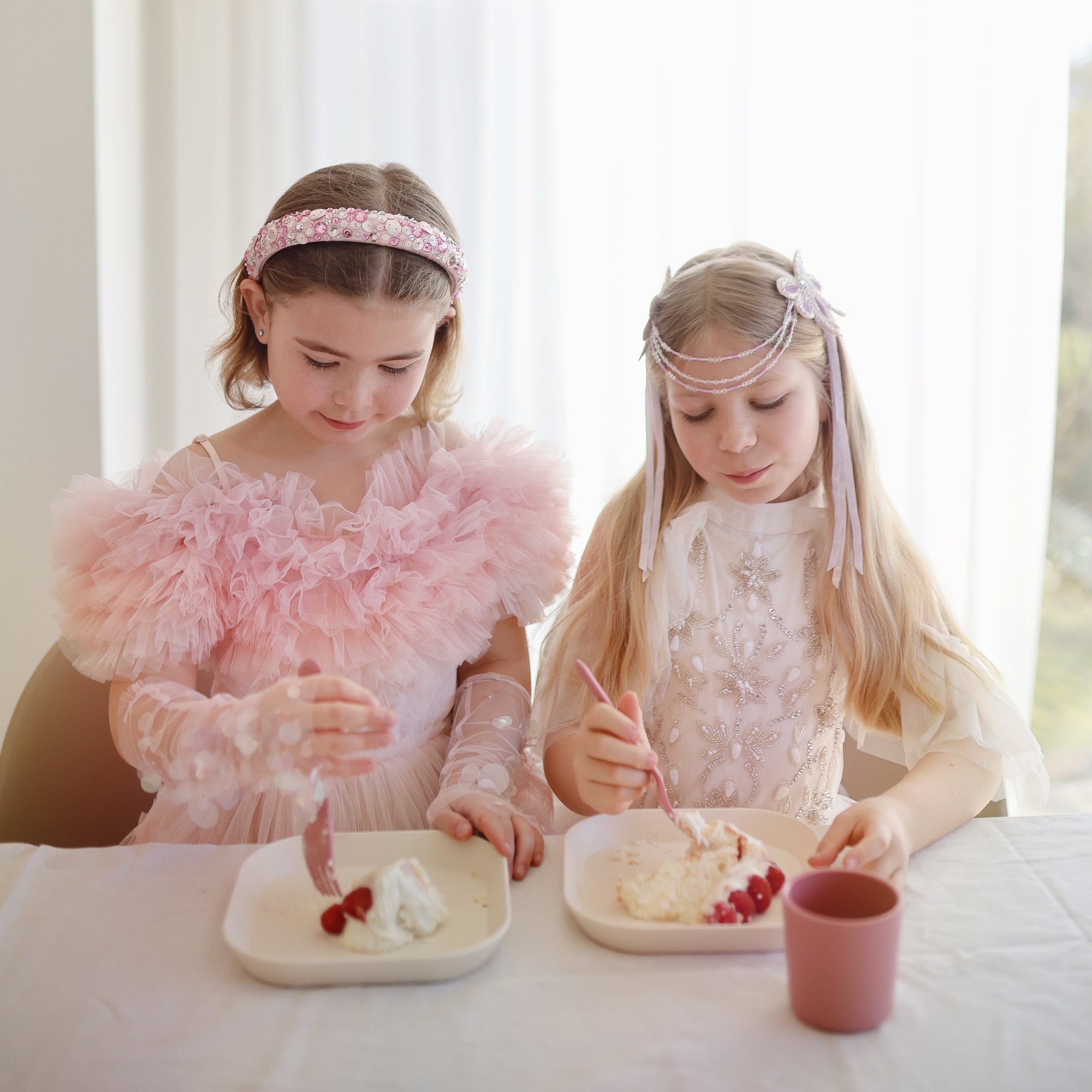 Two girls enjoy dessert with mushie Square Dinnerware Plates, BPA-free and dishwasher safe.