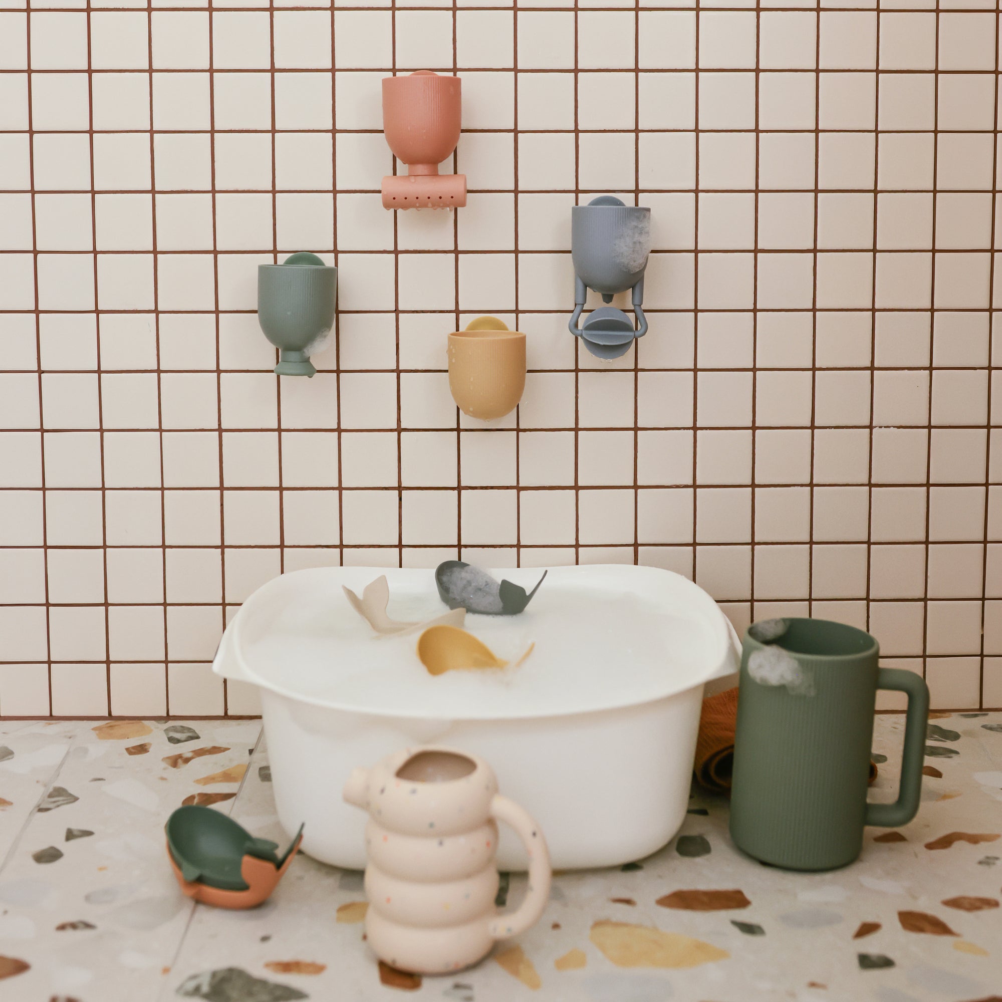 Mushie Pour and Play Bath Set: toy whales and cups for sensory fun by the bath basin.