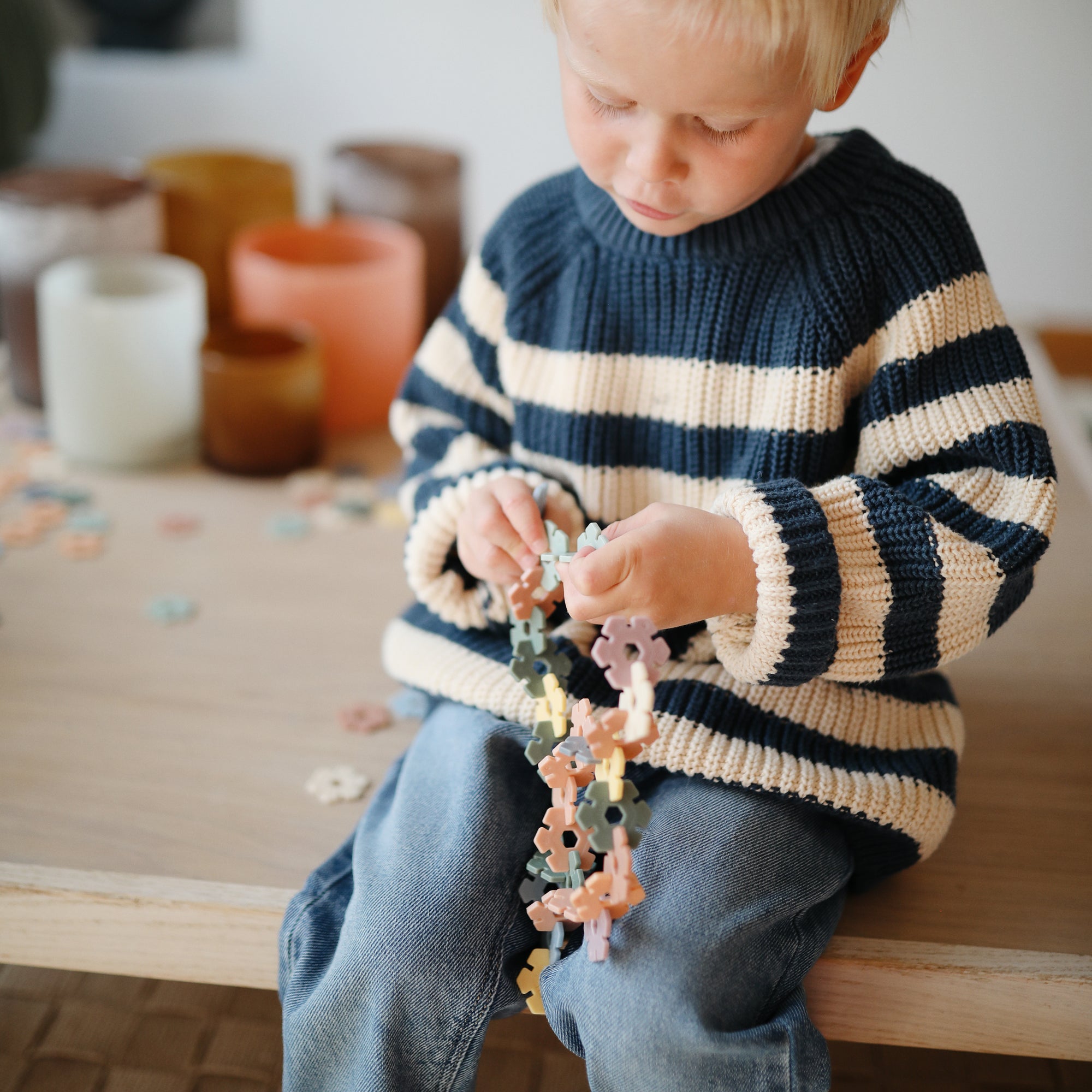 Young child plays with mushie HEX Connect Building Toy Set at a table.