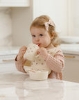 Toddler drinks from Feeding Kit Heart Ditsy by Rylee + Cru, wearing bib at kitchen counter.