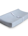 The mushie Extra Soft Muslin Changing Pad Cover is shown on a contoured white pad with safety straps, designed for changing babies, displayed on a plain white background.