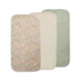 Three Mushie Changing Pad Liners are shown overlapping: one with a floral print, one in solid cream, and one in solid sage green. Each liner has rounded corners and a soft, quilted organic cotton texture.