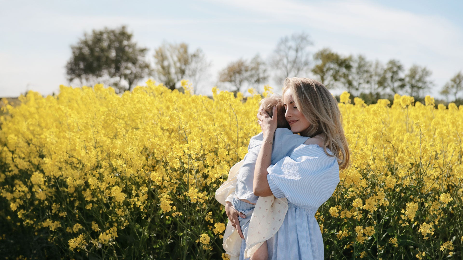 Woman holding a child in a field of yellow flowers
