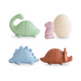 The mushie Dino Mold Free Bath Play Set features four colorful dinosaur-shaped silicone bath toys in green, purple, blue, and brown plus a cream cracked egg toy, all arranged on a white background.