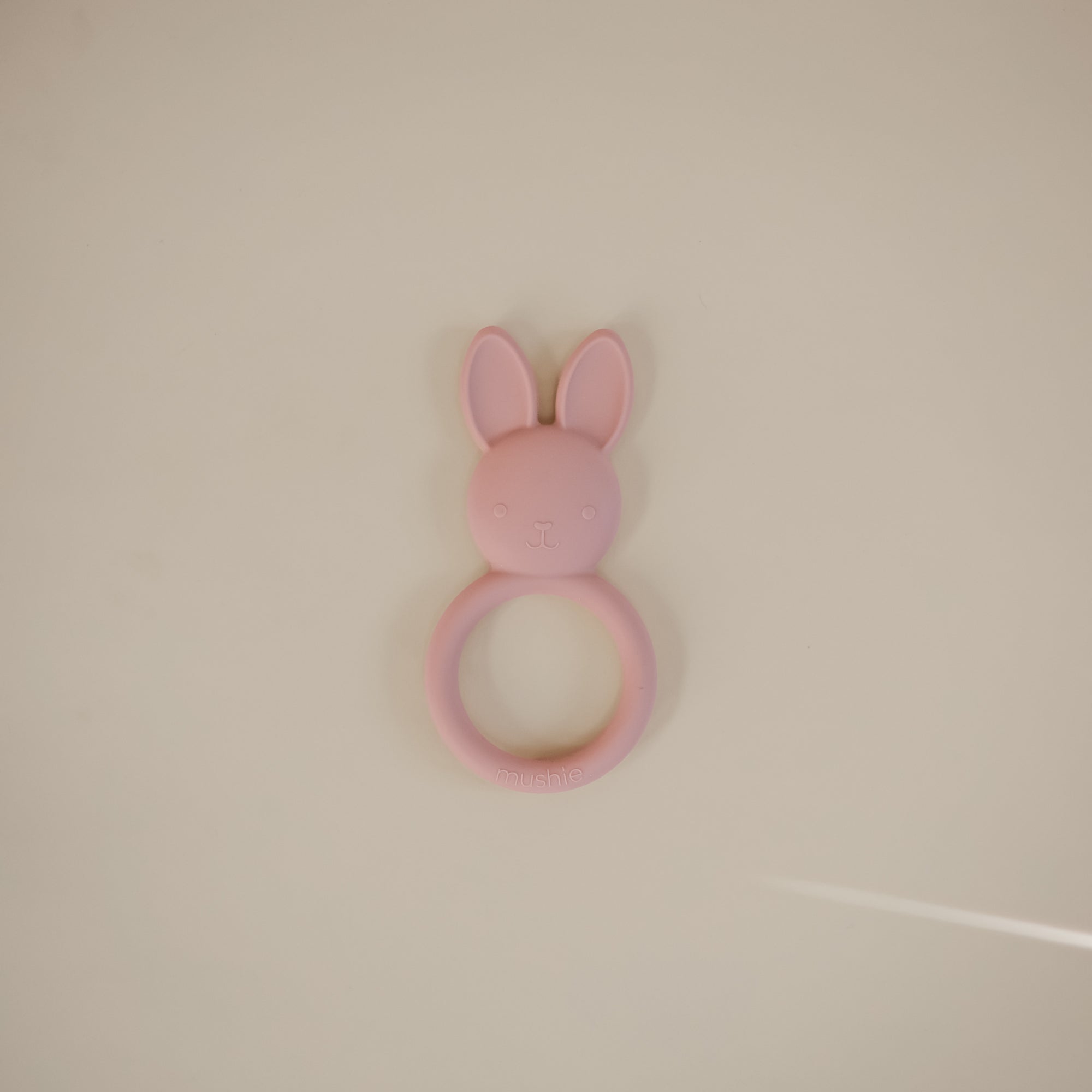 The mushie Bunny Teether is a pink silicone, non-toxic teether for soothing little gums.