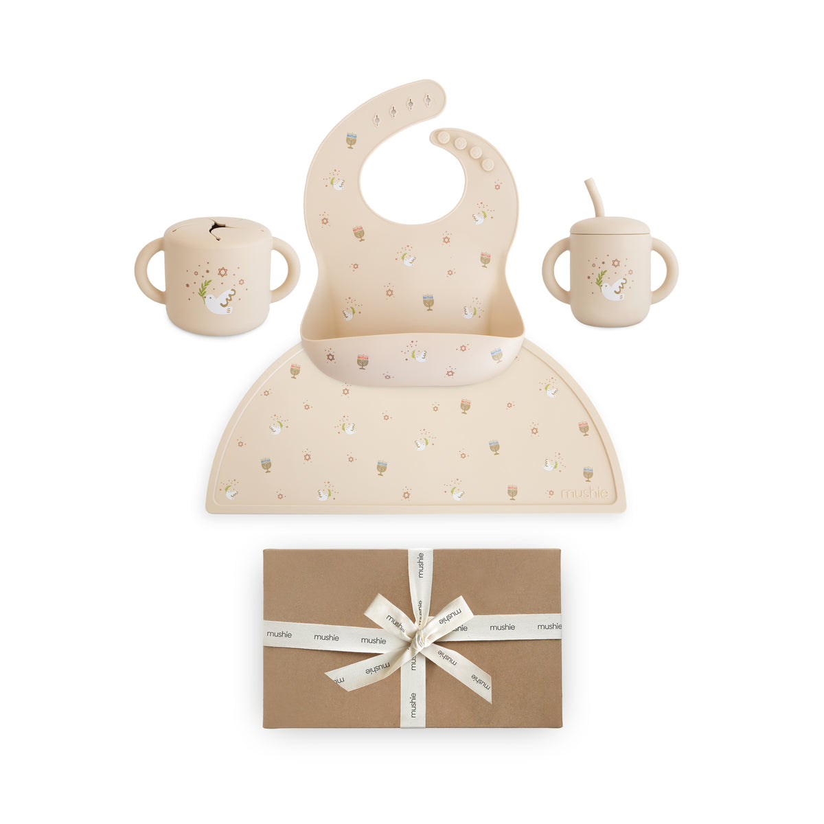 Mushie Hanukkah Doves Feeding Kit with a silicone bib, placemat, and cups above a gift box.