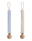 Mushie Linen Pacifier Clip 2-Pack: light blue & beige clips with wooden clasps, side by side.