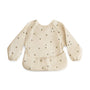 The mushie Long Sleeve Bib in Bees features water-resistant fabric, elastic cuffs, a bottom pocket, and a charming bee pattern—ideal for keeping little ones clean during meals.