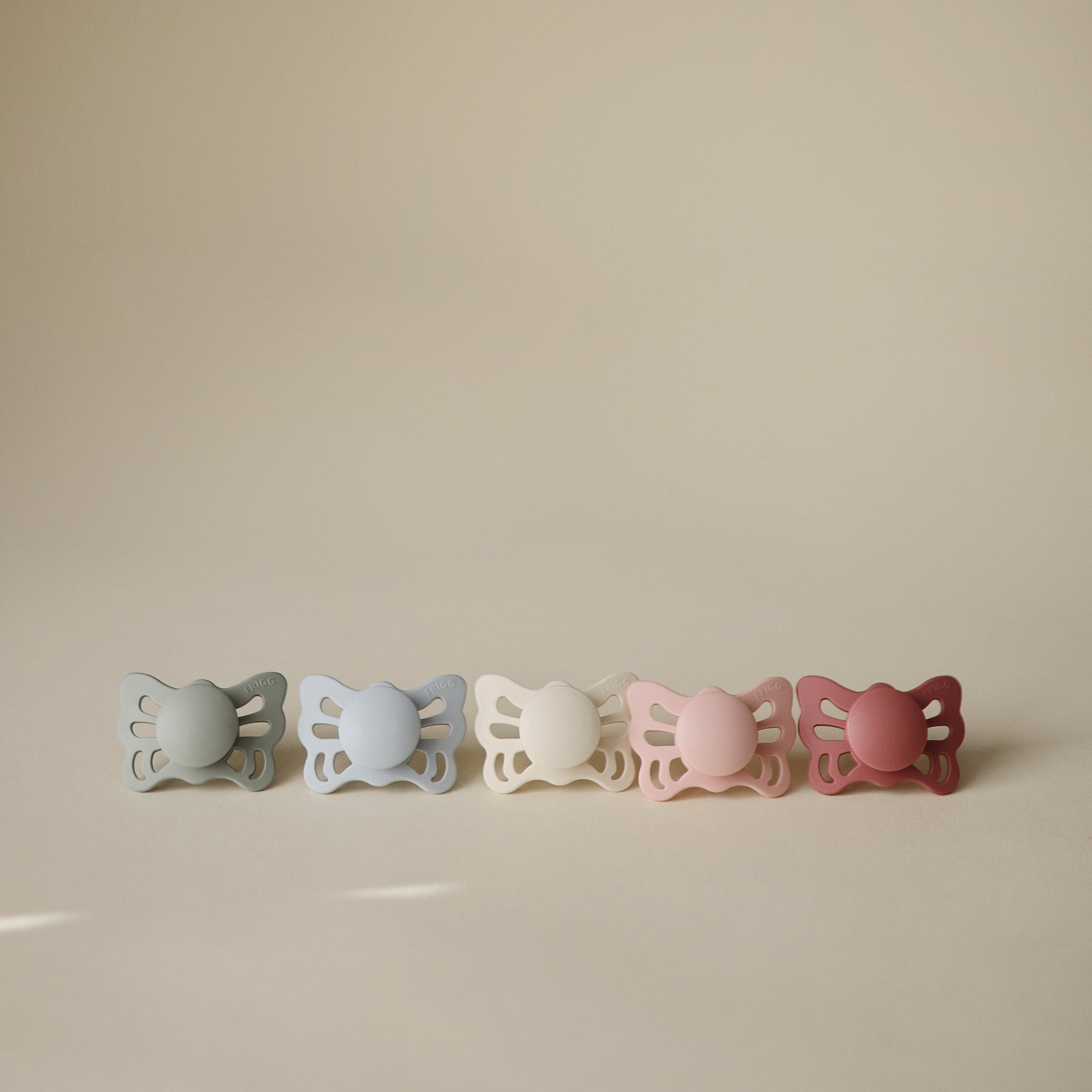 FRIGG Butterfly Anatomical Silicone Pacifier 2-Pack (0-6M) in pastel tones on display.