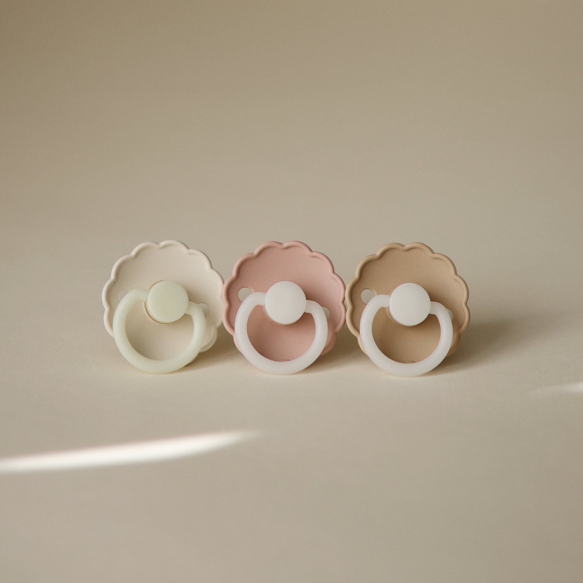FRIGG Daisy Night Natural Rubber Pacifiers, 2-pack, displayed on a beige surface.