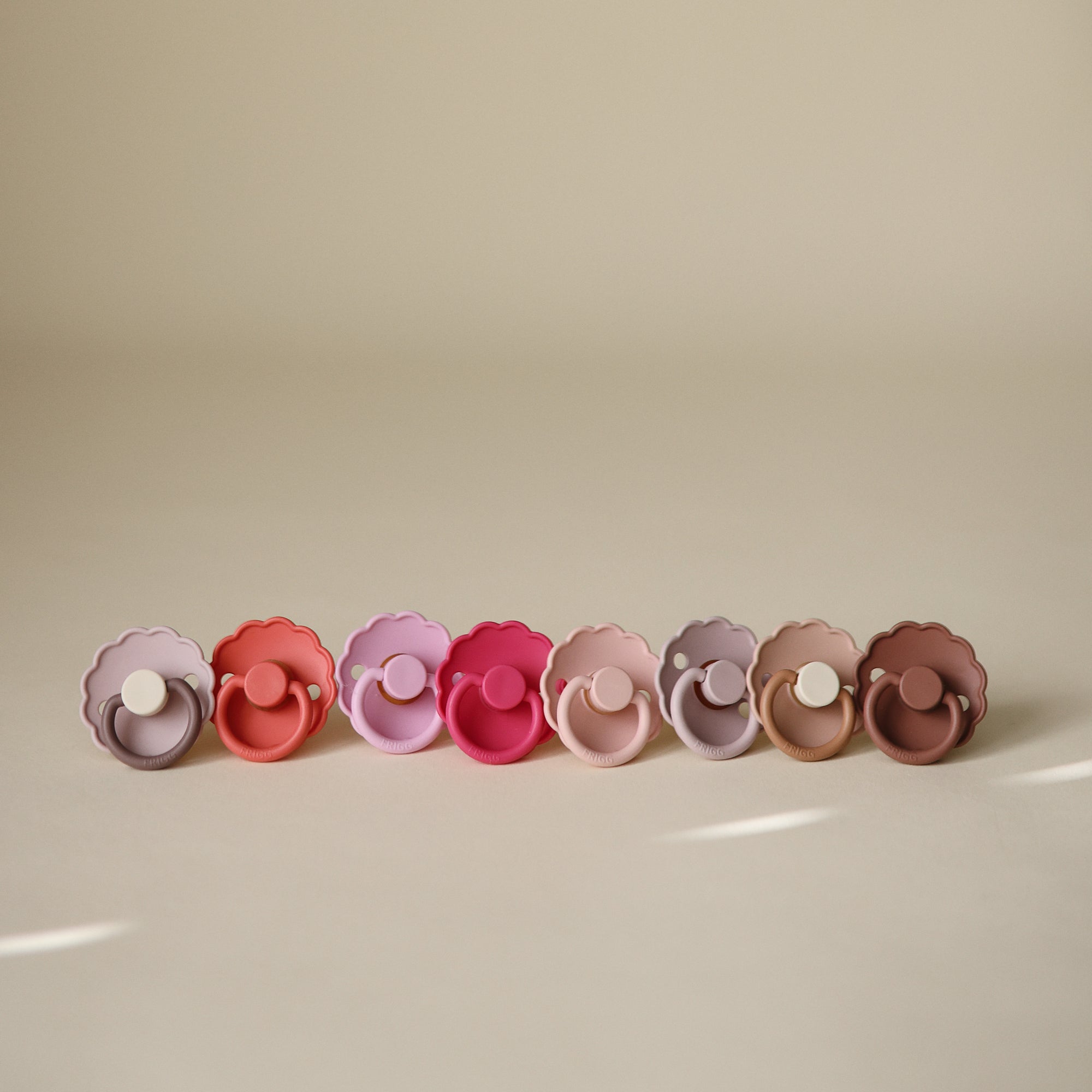 Two pastel FRIGG Daisy Natural Rubber Pacifiers on a neutral background.