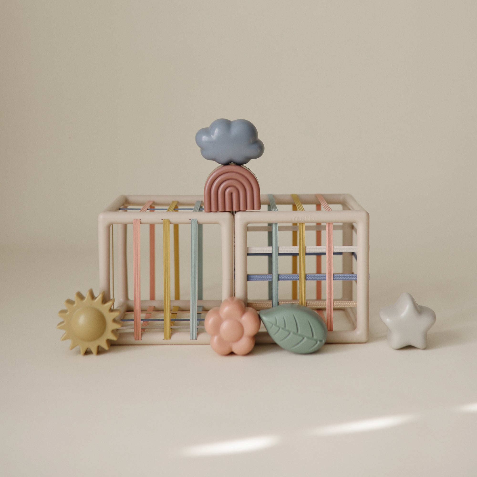 The mushie Elastic Shape Sorter boosts fine motor skills with fun shapes for tactile play.