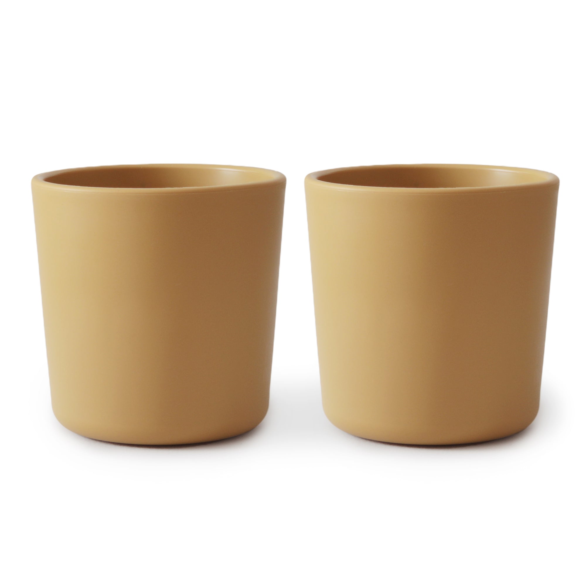 Two identical mushie Dinnerware Cups for kids, plain and light brown, are placed side by side on a white background.