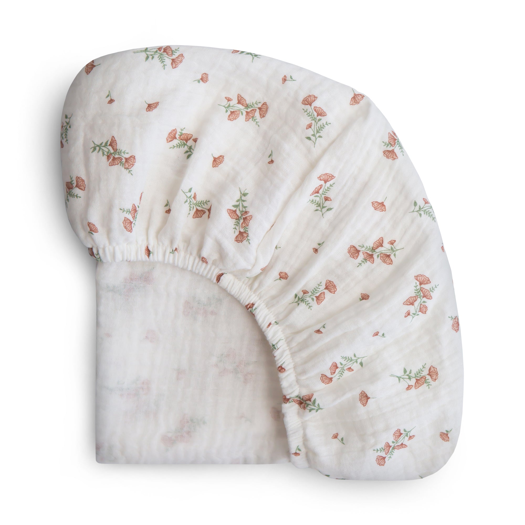 Mushie Extra Soft Bassinet Muslin Crib Sheet in white with pink floral pattern, neatly folded.