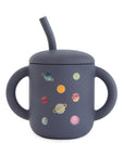 Mushie Silicone Training Cup + Straw, dark with 2 handles and colorful planet print.