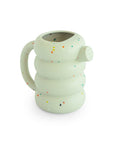 Mushie Silicone Watering Can: round, white, speckled; thick handle resembles a bath toy.
