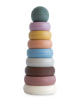 The mushie Stacking Rings Toy features nine pastel, non-toxic, donut-shaped rings with a round top, stacked in decreasing size from bottom to top, displayed against a white background.