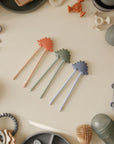 Three mushie Training Chopsticks with pastel baby self-feeding utensils.
