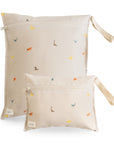 Two beige mushie Water Resistant Wet bags with a dinosaur print and side carry straps.