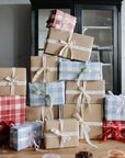 Playtime Gift Set by mushie sits on a wooden table in front of a cabinet, wrapped with ribbons.