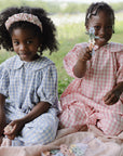 Two girls play with the mushie HEX Connect Building Toy Set, smiling on a picnic blanket.