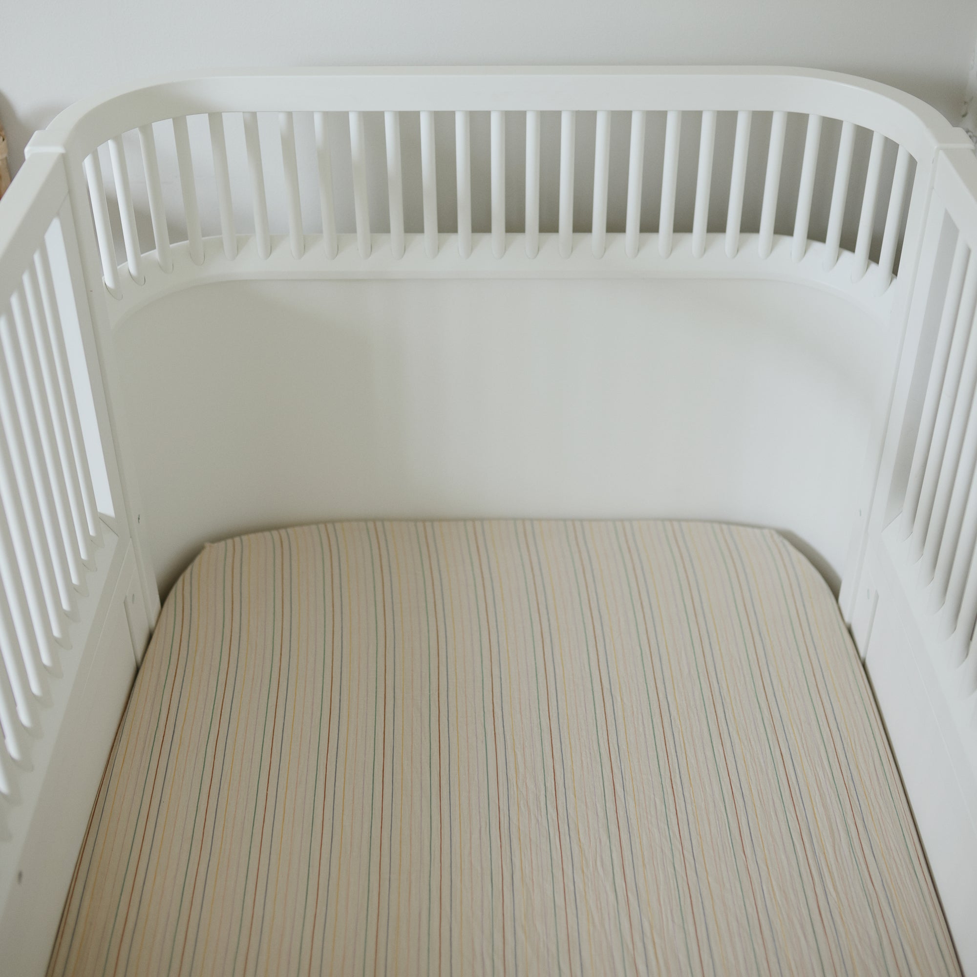 Mushie Extra Soft Muslin Crib Sheet on a white crib in a clean, minimal nursery setting.
