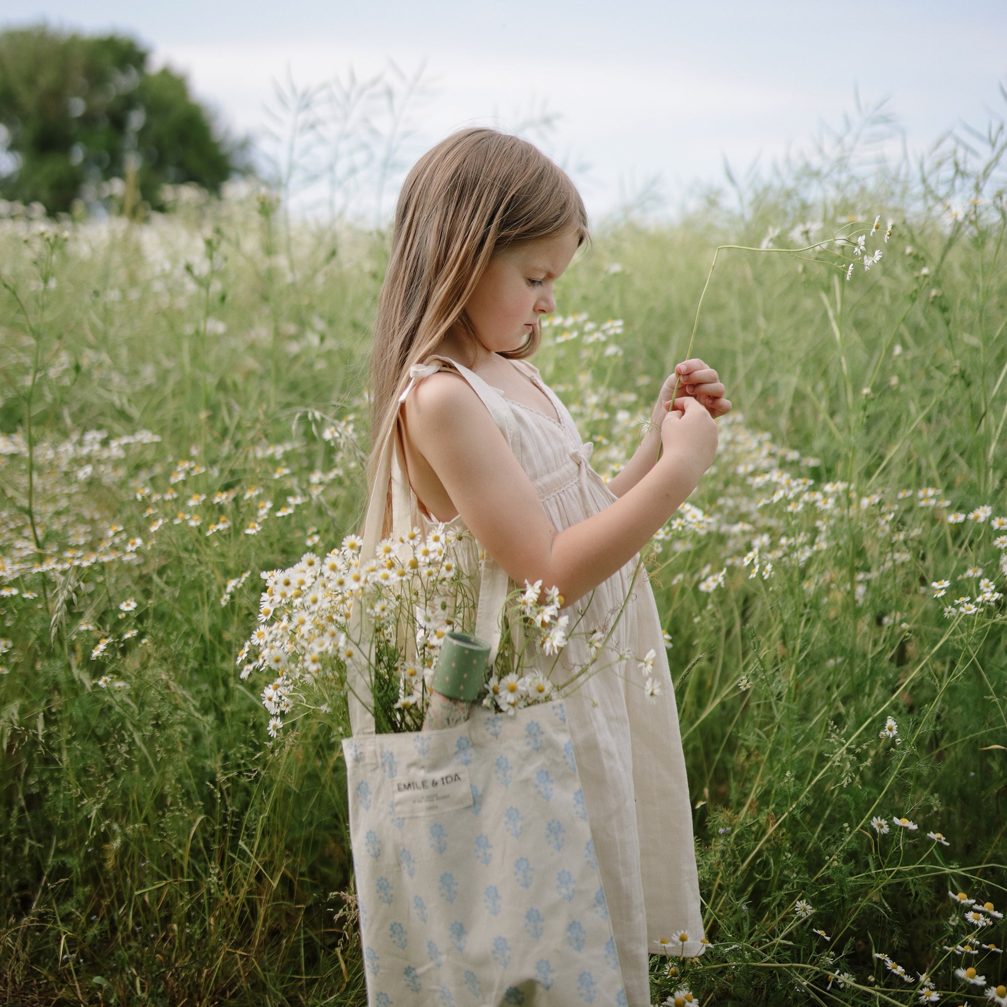 Young girl explores a field holding wildflowers and mushie Kaleidoscopes.