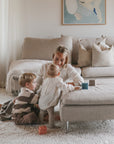 A woman and two kids play with mushie's Mix and Match Toy, building fine motor skills.