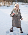 Girl plays with mushie Mix and Match Toy outside in snow, practicing fine motor skills.