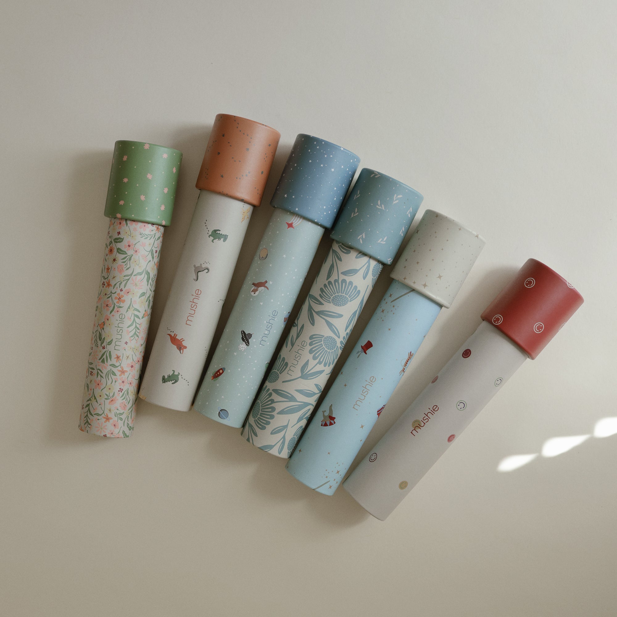 Six mushie Kaleidoscopes with colorful caps, ideal for exploratory play.