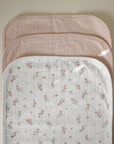 Three Mushie Changing Pad Liners: two solid pink and one white with a floral print.