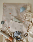 Two mushie Water Resistant Wet bags surrounded by baby teethers and pacifiers.