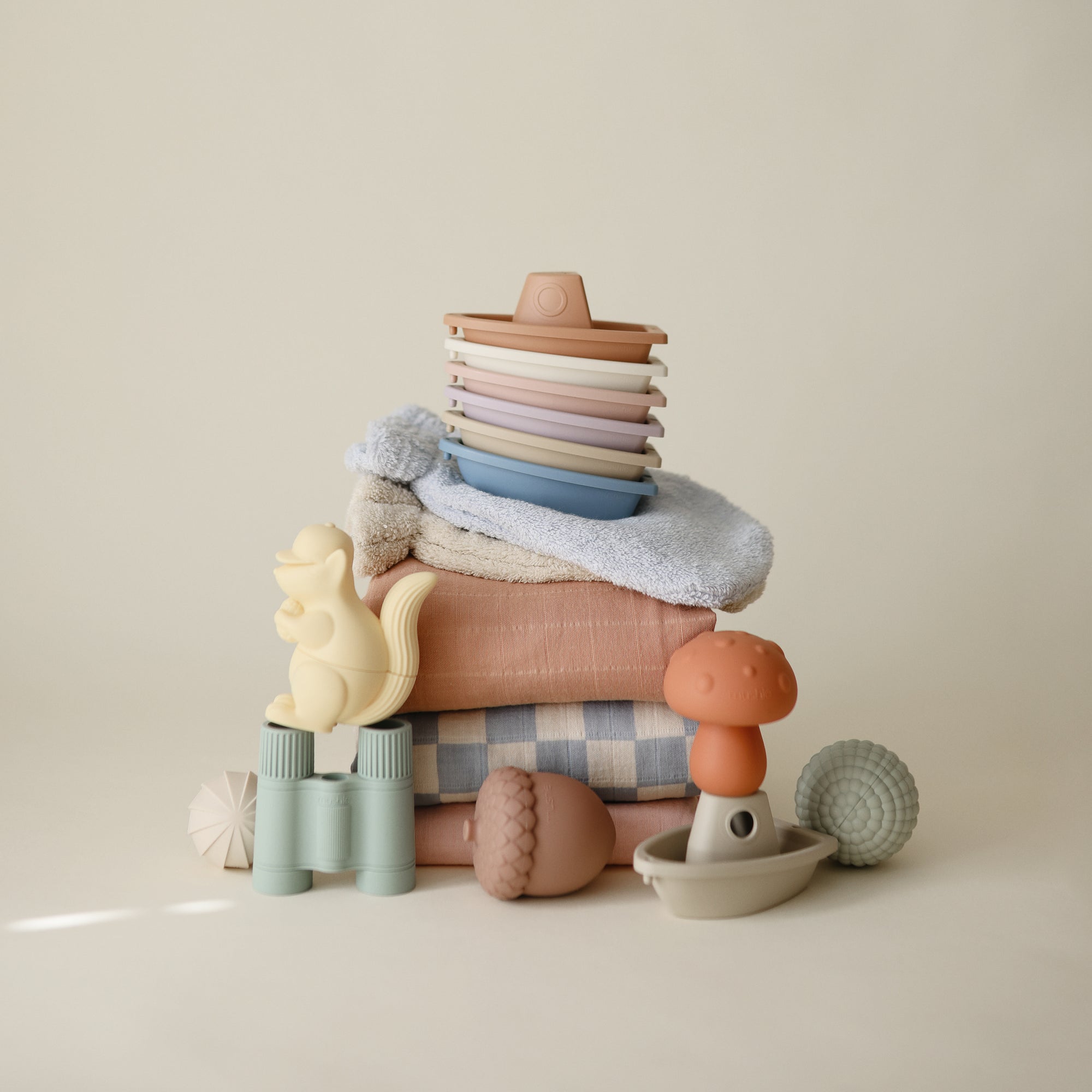 Mushie Mold Free Bath Play Set and pastel towels arranged on a light background.