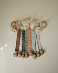 Mushie Linen Pacifier Clip 2-Pack: pastel linen clips with wood & silicone, on cream surface.