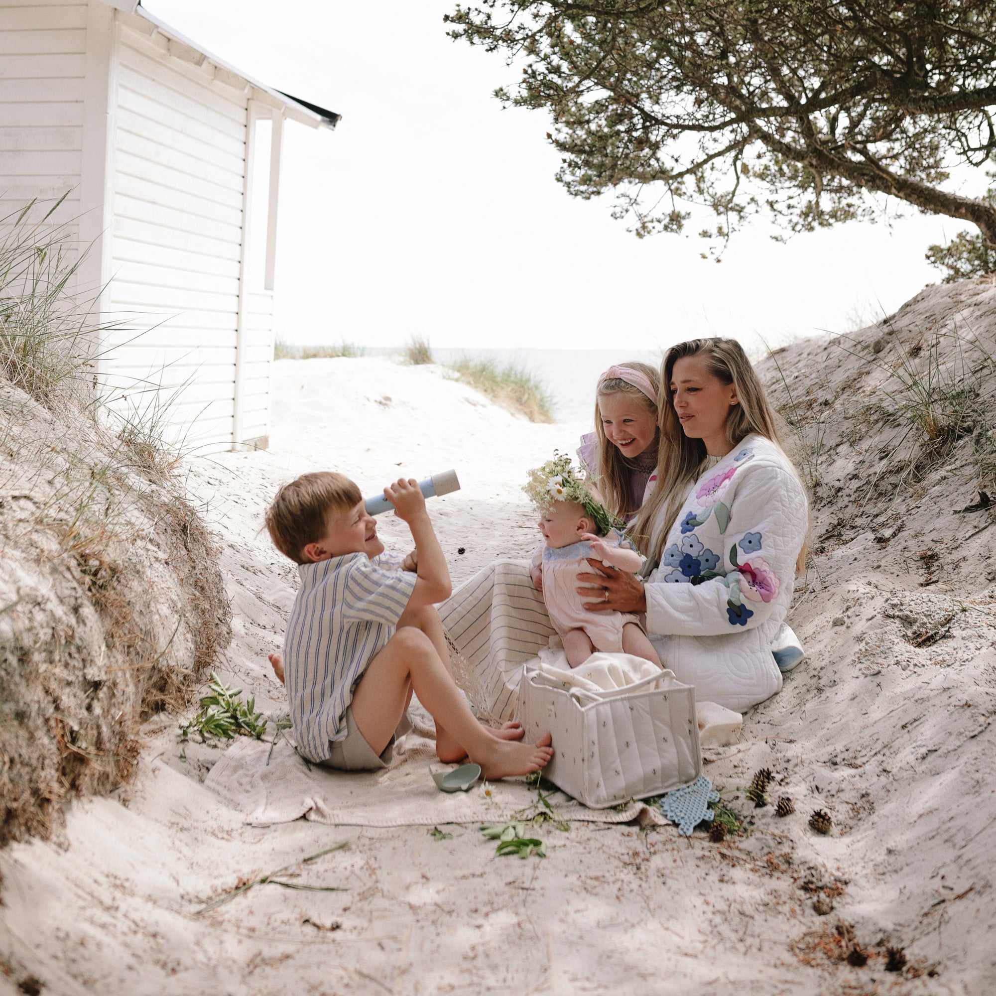 A family picnics on sand as kids play with mushie Kaleidoscopes.
