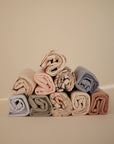 Mushie Changing Pad Liners stacked in a pyramid shape on a neutral background.