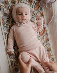 Baby in pink on floral blanket, resting on Mushie Changing Pad Liners.