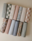Mushie Changing Pad Liners: 12 organic cotton pieces in pastel floral or checkered patterns.