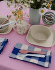 Mushie Silicone Training Cup + Straw featured in a children’s table setting with bowls and utensils.