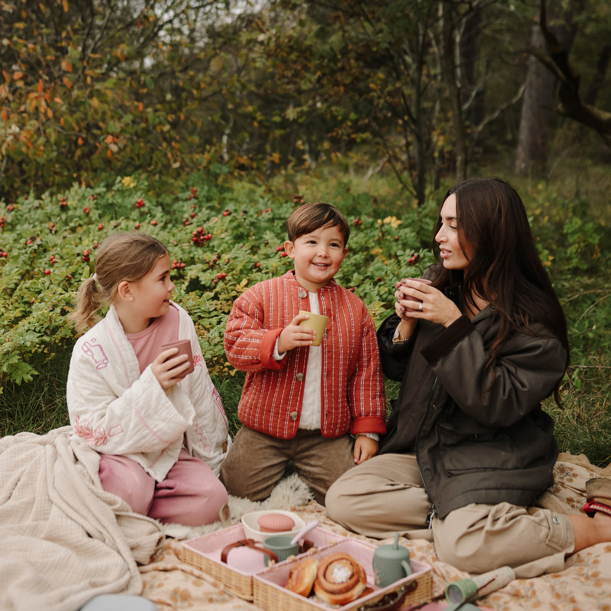 A woman and two children use mushie Square Dinnerware Bowls for a pretend tea party.