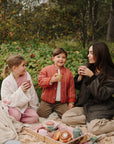 A woman and two children use mushie Square Dinnerware Bowls for a pretend tea party.