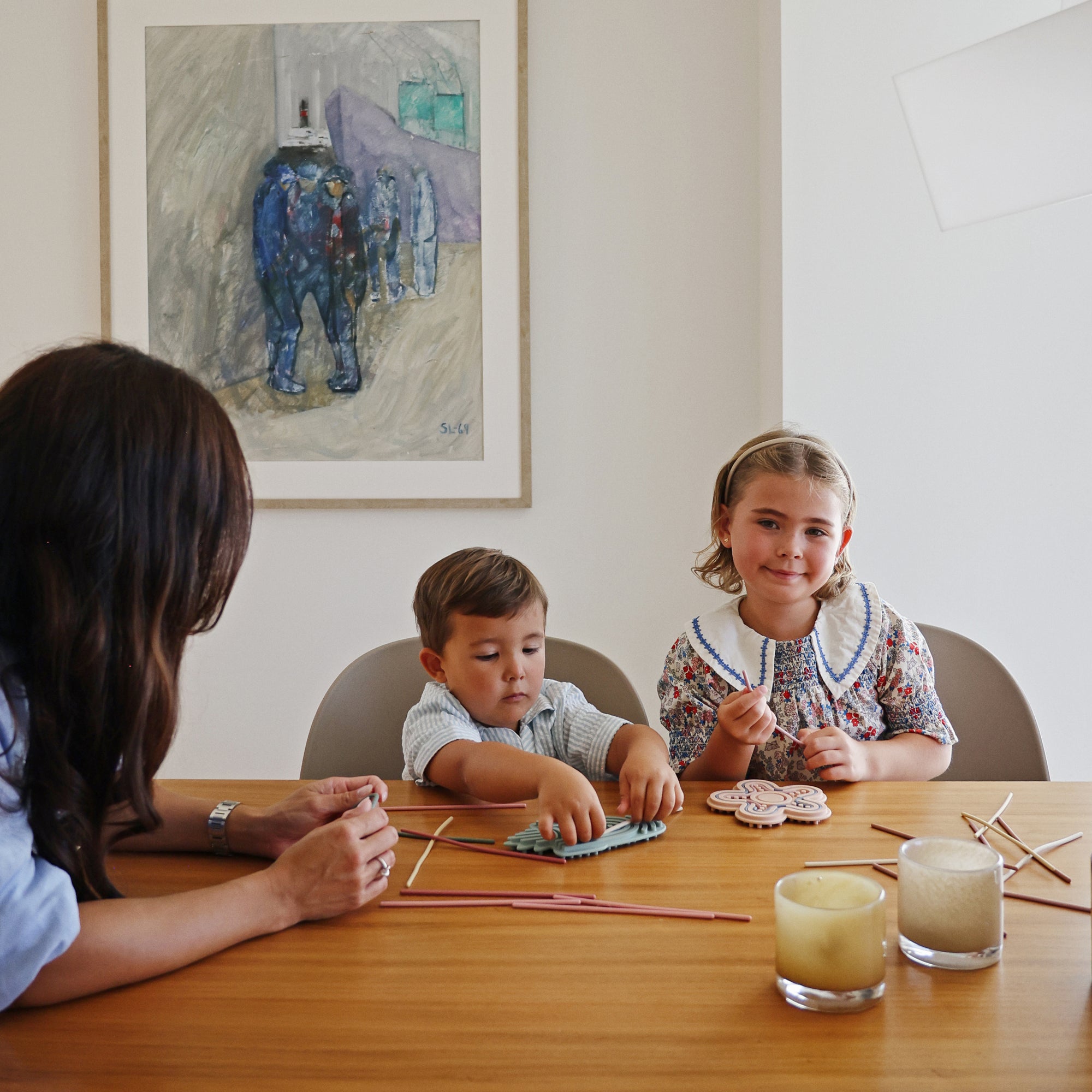 A woman and two kids play with a mushie Silicone Sensory Toy at a table in a modern room.