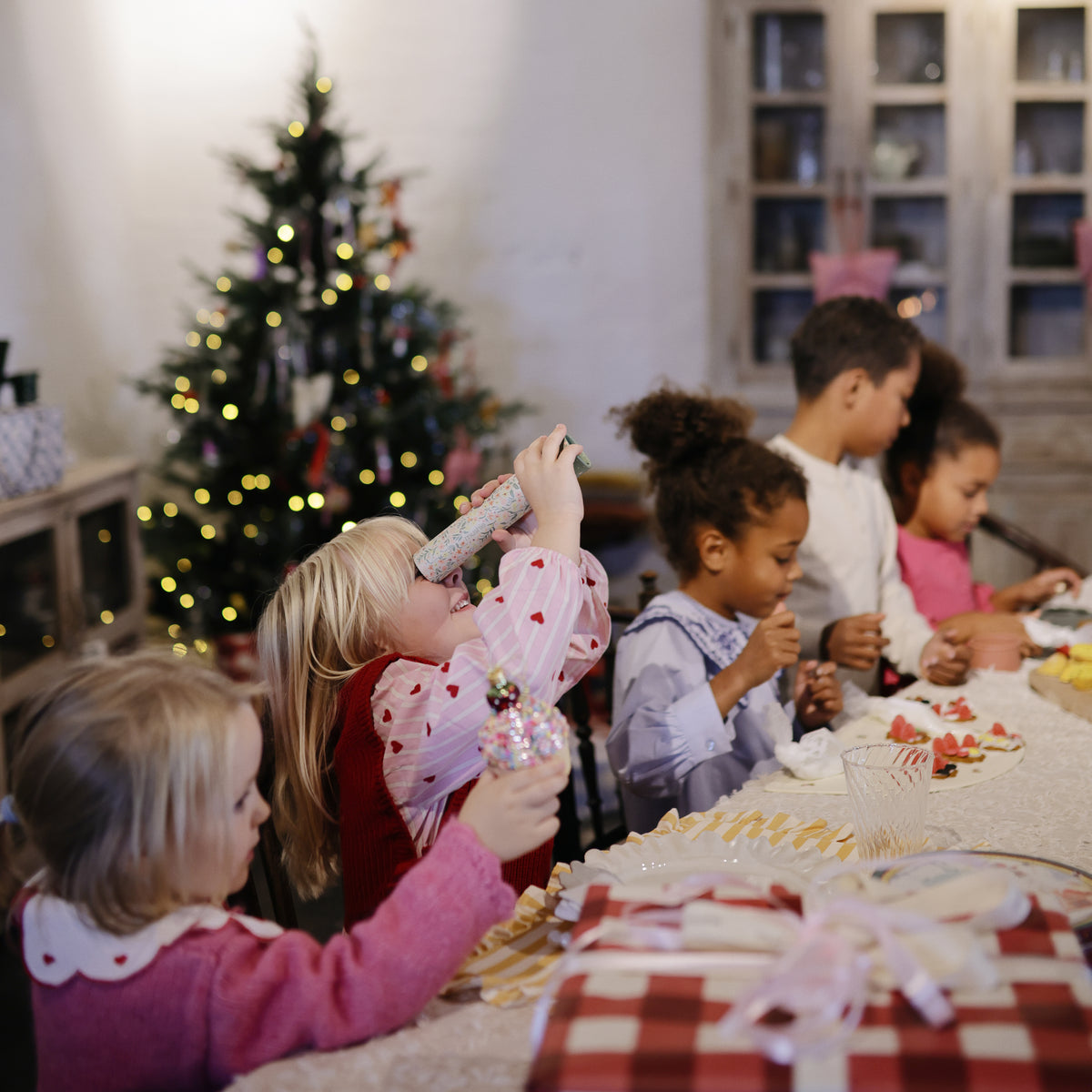 Kids decorate cookies as timeless toys while mushie Kaleidoscopes spark playful exploration nearby.