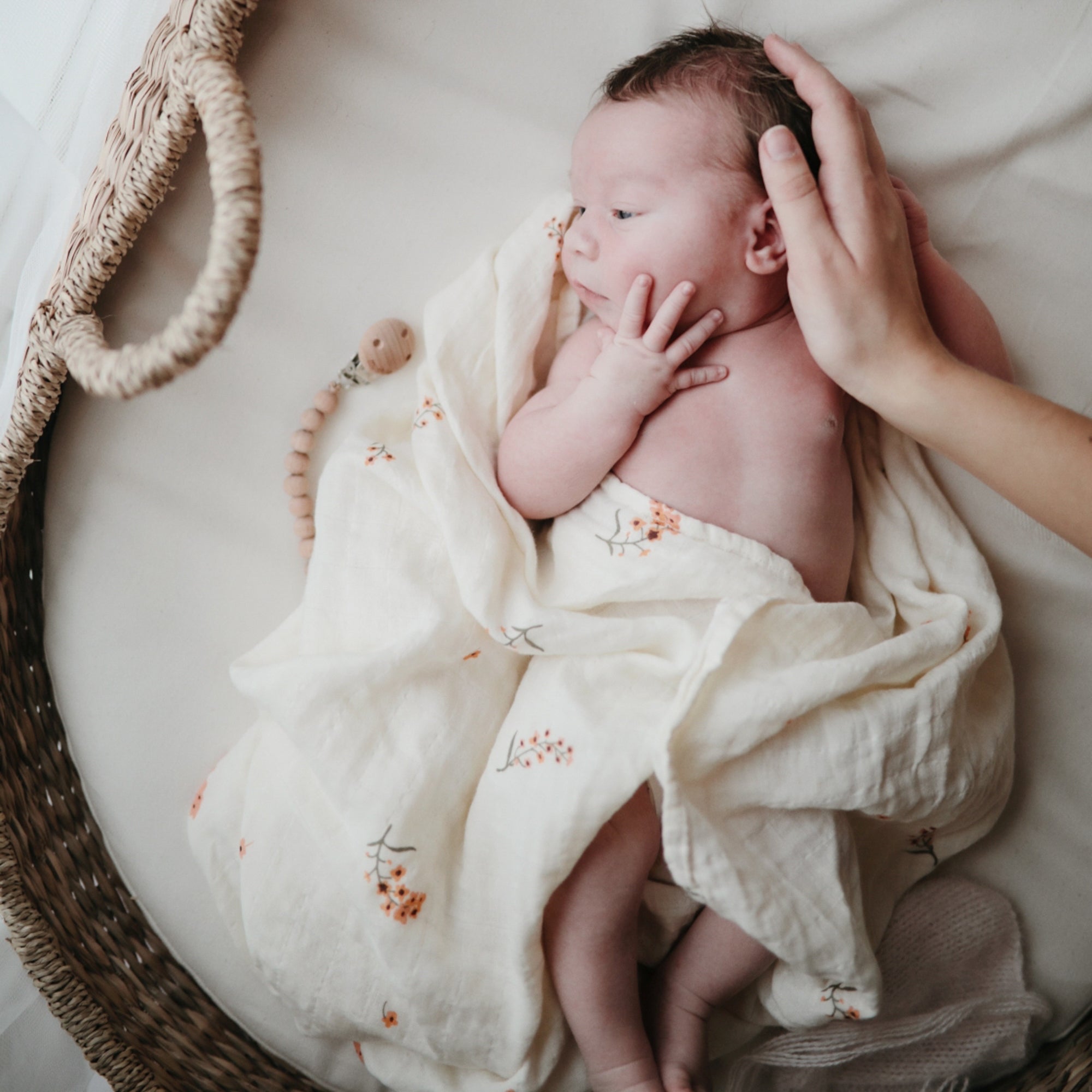Lifestyle image of a baby swaddled in organic cotton swaddle in Flowers